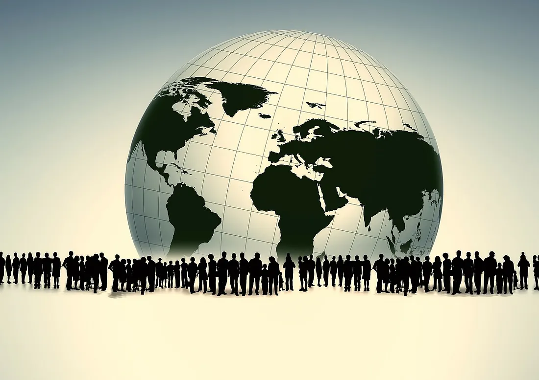 A large, grid-lined globe showing the continents of Earth sits in the background against a light, desaturated sky. In the foreground, a diverse crowd of people is represented as a solid black silhouette standing together in a long line.
